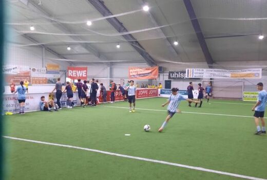 Training in der Fußballhalle, ein Spieler im Zentrum setzt zum Schuss an.