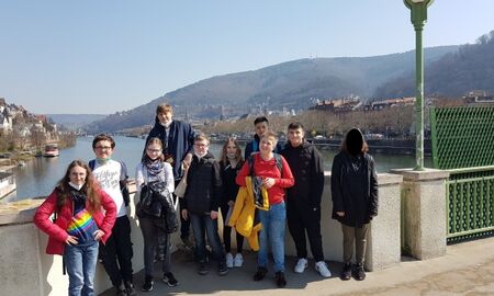 10 Schüler*innen stehen auf der Neckarbrücke, im Hintergrund der Neckar und die Hügel