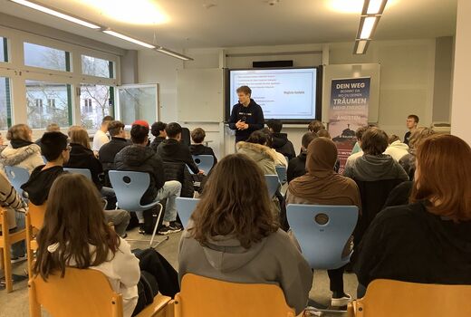 Schülerinnen und Schüler sitzen im Klassenzimmer und hören einen Vortrag