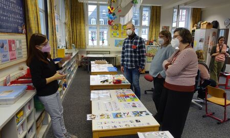 Vier Personen stehen um Tische, die mit Fördermaterialien bedeckt sind