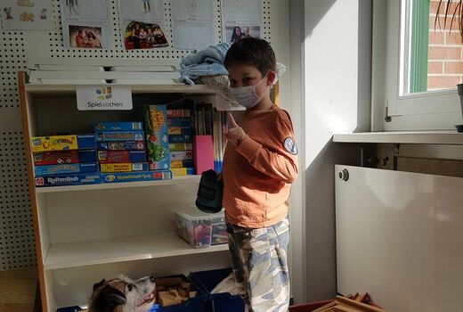 Schüler zeigt mit dem Finger auf einen Hund der vor ihm sitzt und dem Schüler aufmerksam zuschaut, Kind gibt Hund das Kommando Sitz