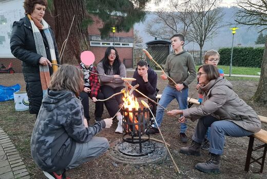 SchülerInnen und ErzieherInnen garen Stockbrot am Feuer