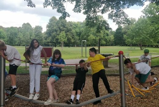 Schüler balancieren über eine Strickleiter und einen Balken. Dabei halten sie sich an einem Seil fest.