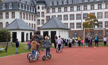 eine Gruppe Kinder saust mit den Rollern auf dem Schulhof