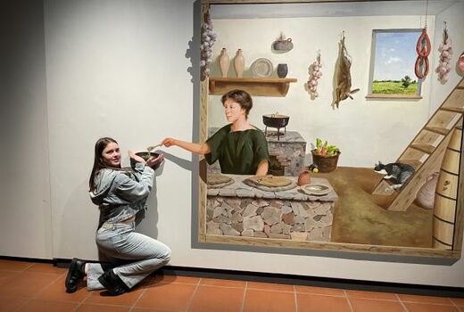 Illusion: Auf dem Bild sieht man eine Taverne. Eine Frau schöpft einer Schülerin etwas in eine Schale.