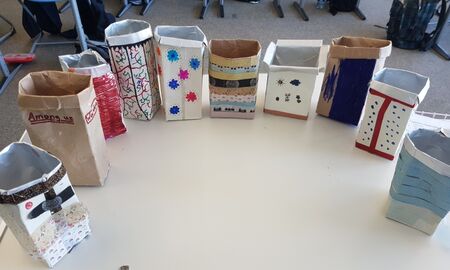 Auf einem Tisch stehen zehn upgecycelte Milchtüten im Halbrund.Sie sind bunt beklebt und bemalt.