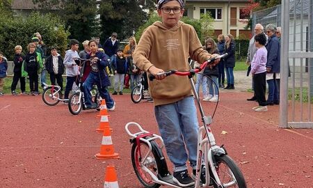 ein Junge fährt mit dem Roller durch Hütchen