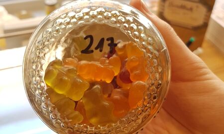 Eine Hand hält ein Glas mit Gummibärchen.