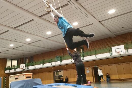 Zwei Personen schwingen an Ringen.