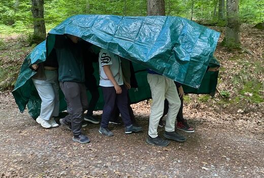 Eine Gruppe SchülerInnen läuft unter dem Schutz einer blauen Plane.